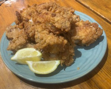 A plate of fried chicken pieces served with two lemon wedges on a blue plate.