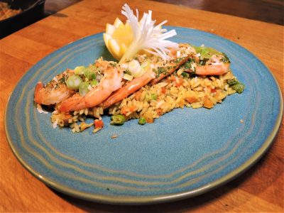 Shrimp and vegetable fried rice garnished with green onions, served with lemon wedges and a white vegetable flower.